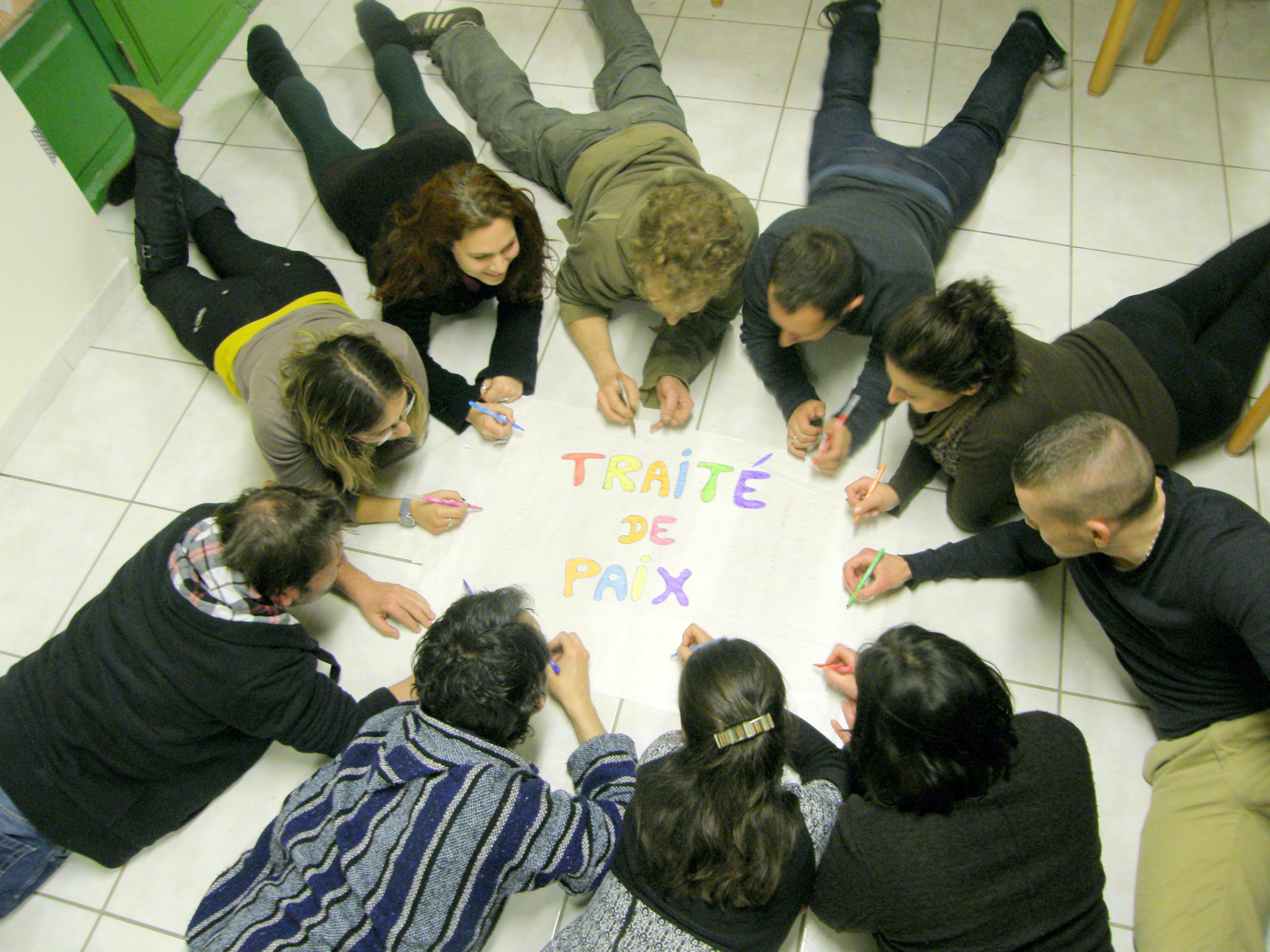 Groupe de stagiaires formant un cercle autour d'une affiche Traité de paix